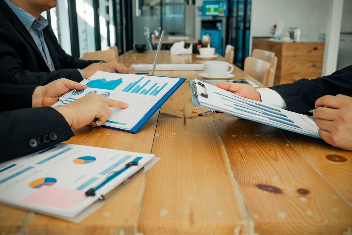 Businesspeople analyzing investment graph meeting brainstorming and discussing plan in meeting room, investment concept